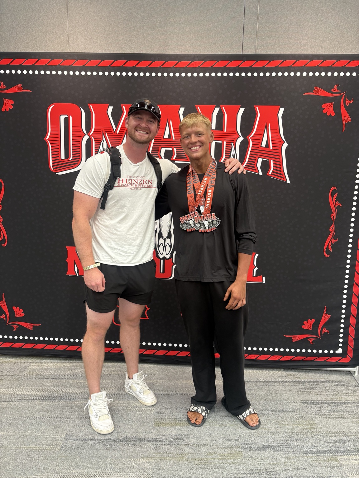 Dawson Heinzen standing with a Heinzen Health and Fitness client after competing in Omaha